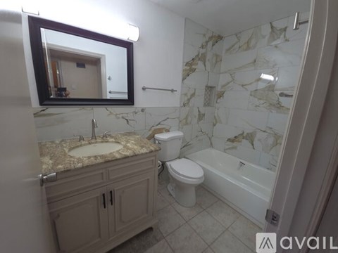 A bathroom with a marble patterned shower and a sink.