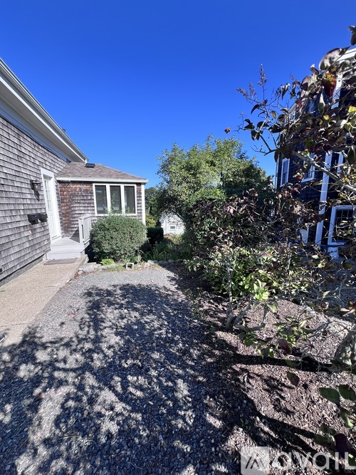 A sunny day in a residential area with a house and a clear blue sky.
