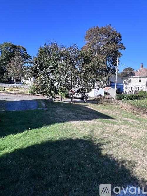 A grassy area with trees and houses in the background.