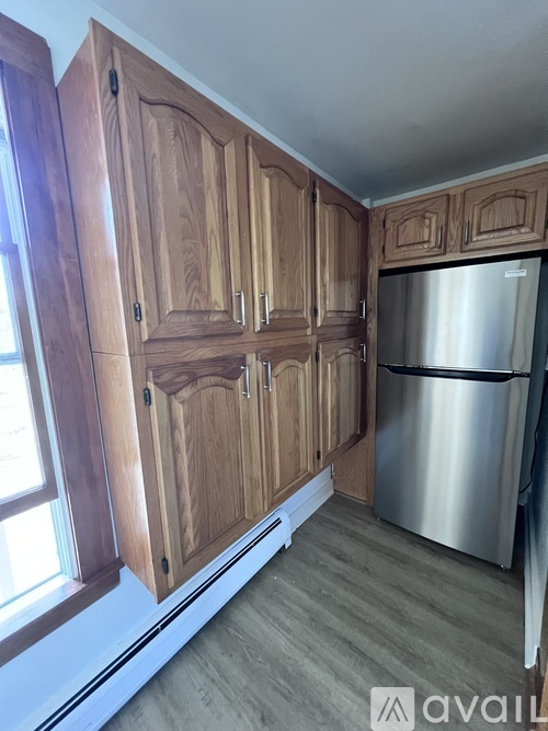 A kitchen with wooden cabinets and a stainless steel refrigerator.