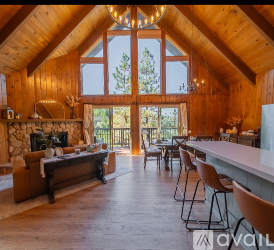 A wooden cabin with a stone fireplace and a large window.