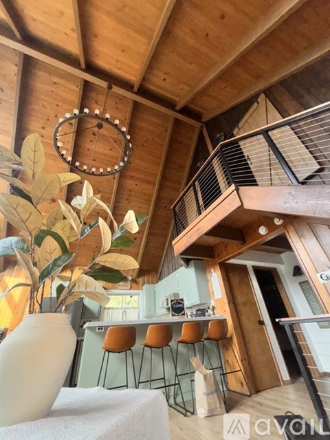 A large vase sits on a table in a room with wooden walls and a hanging circular decoration.
