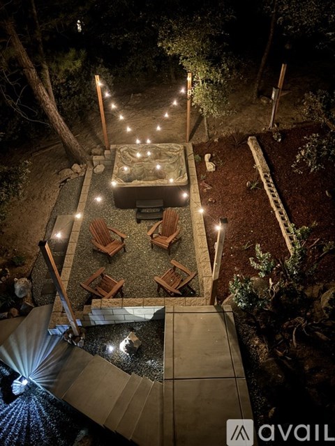 A backyard with a hot tub, patio furniture, and string lights.