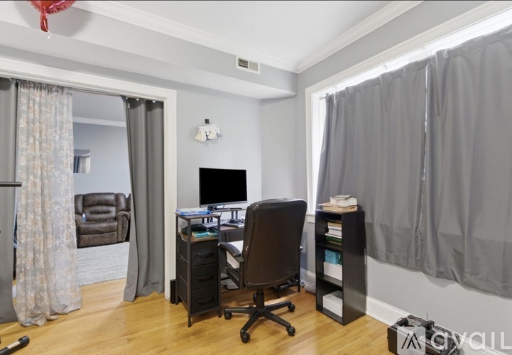 A room with a desk, chair, and a window with curtains.