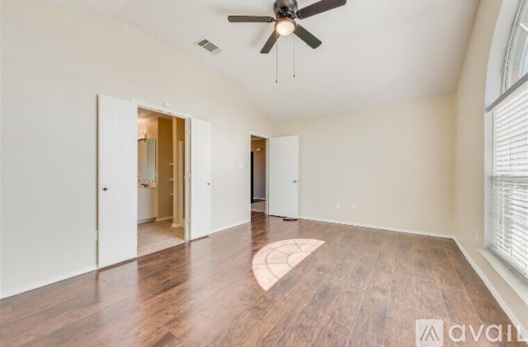 A spacious room with a ceiling fan and wooden flooring.