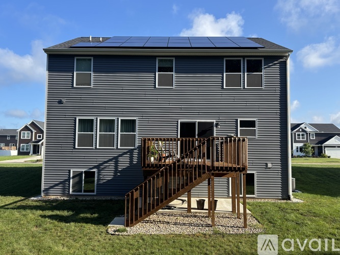 A house with solar panels on the roof and a deck in front.