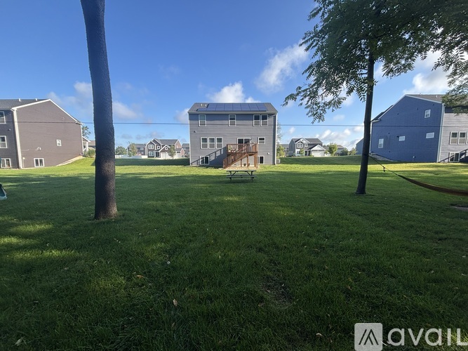 A grassy field with a building in the background and a tree in the foreground.