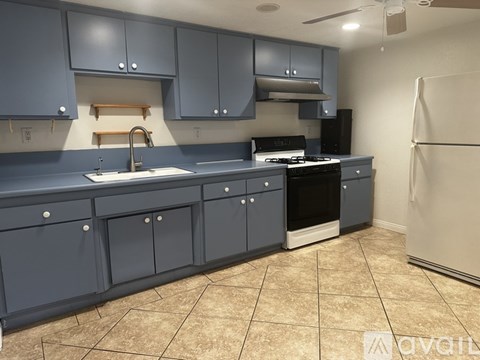 A kitchen with a sink, stove, and refrigerator.