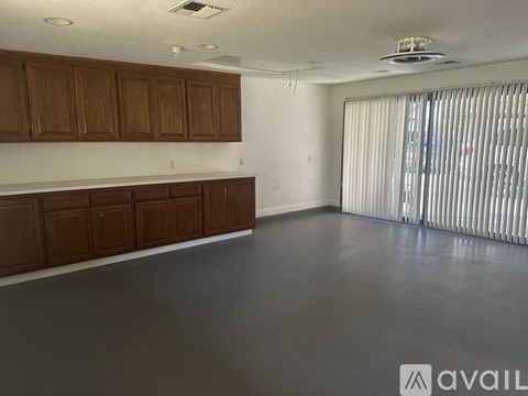 A room with brown cabinets and a window with blinds.