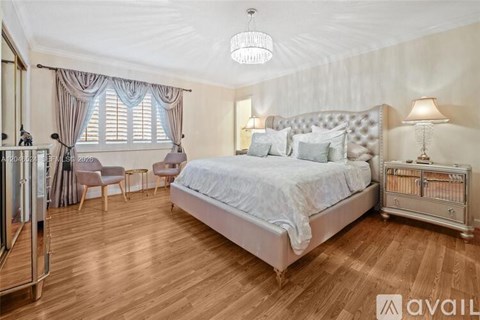 A bedroom with a large bed and a chandelier.