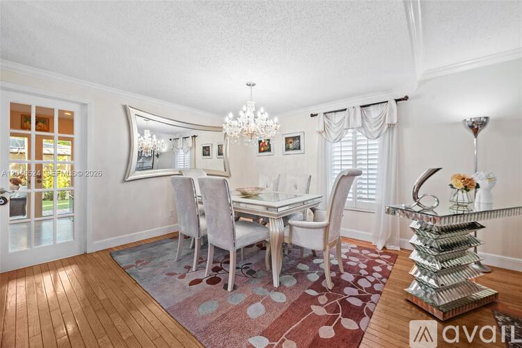 A dining room with a table set for four and a chandelier.