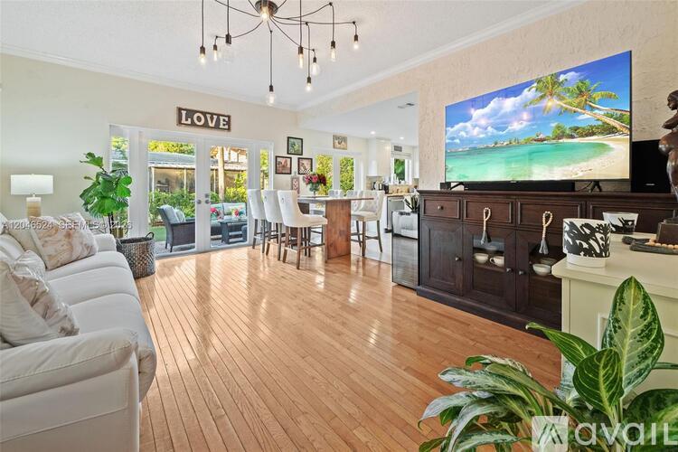 A living room with a white couch and a flat screen TV displaying a beach scene.