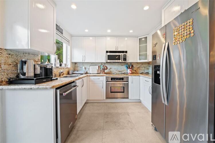 A modern kitchen with a stainless steel refrigerator and white cabinets.