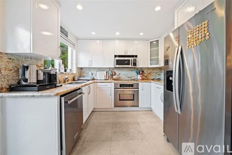 A modern kitchen with a stainless steel refrigerator and white cabinets.