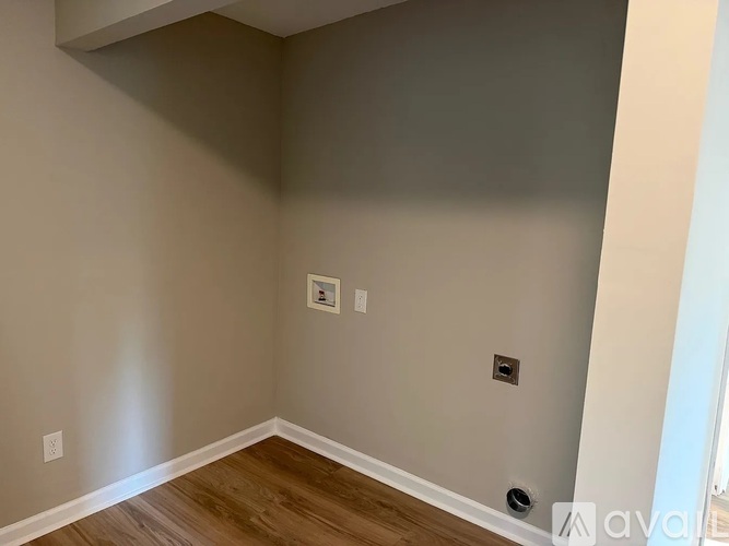 A room with a wooden floor and a wall socket.