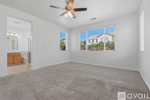 A spacious room with a ceiling fan and a view of a house through the window.