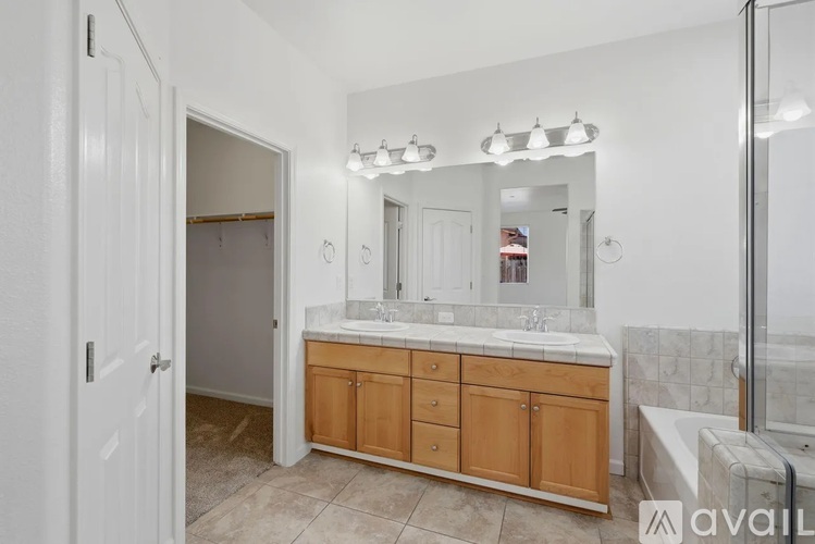 A bathroom with a white door, a mirror, and a wooden cabinet.