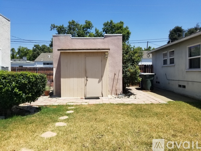 A small building with a tan door is surrounded by a grassy area.