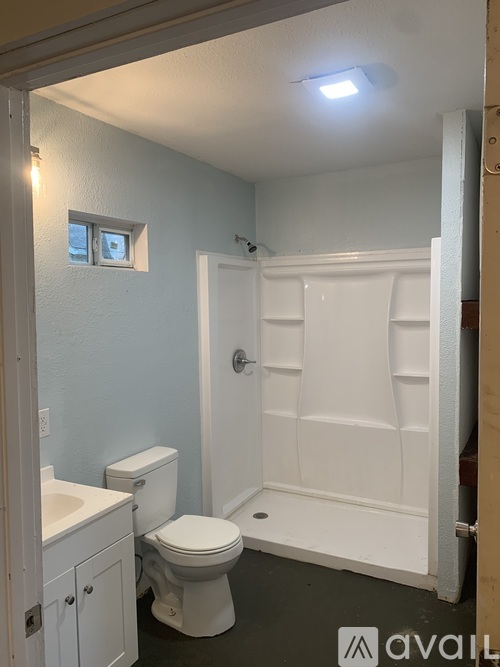 A white bathroom with a toilet, sink, and shower.