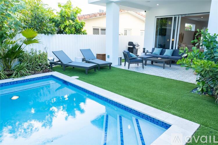 A pool with a white fence and a white house in the background.