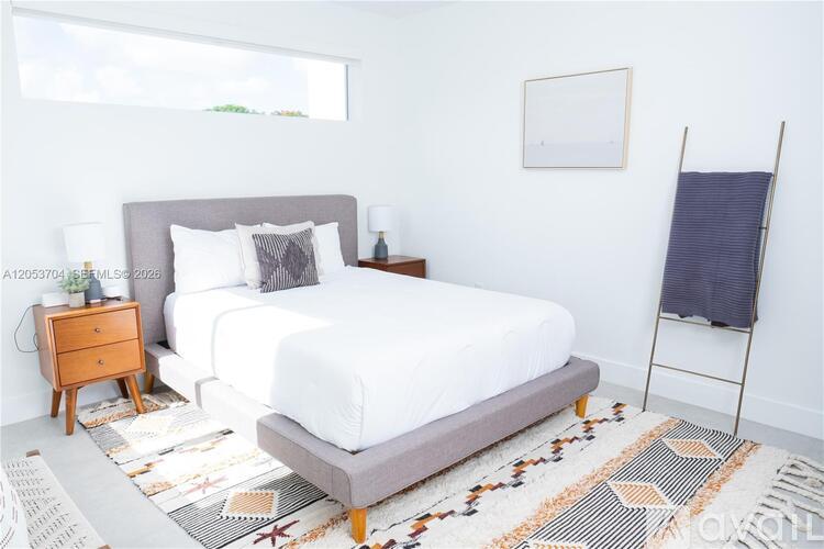 A bedroom with a large bed and a wooden nightstand.