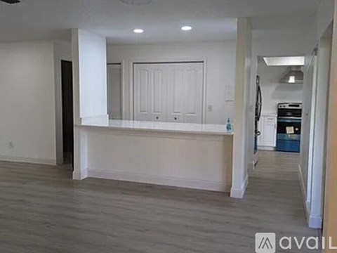 A spacious room with a large white door and a wooden floor.