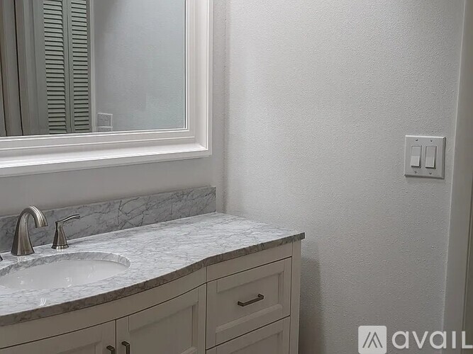 A bathroom with a marble sink and a mirror above it.
