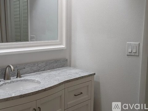 A bathroom with a marble sink and a mirror above it.