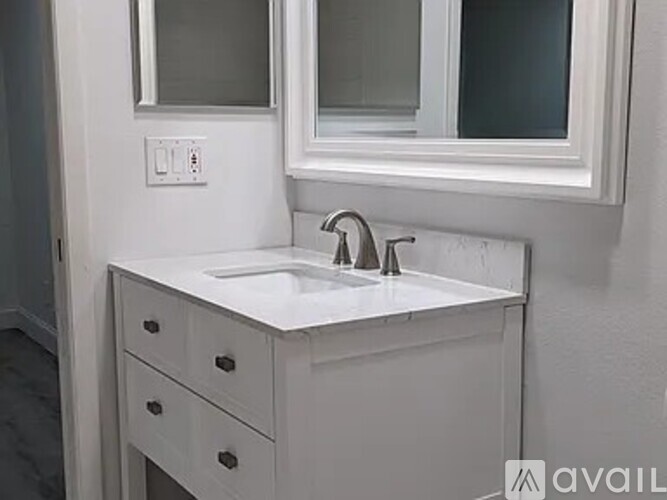A white bathroom vanity with a sink and a mirror above it.