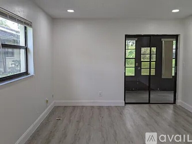 A room with a wooden floor and a glass door leading outside.