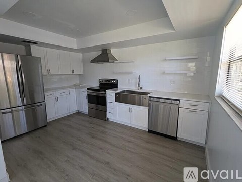 A modern kitchen with white cabinets and stainless steel appliances.