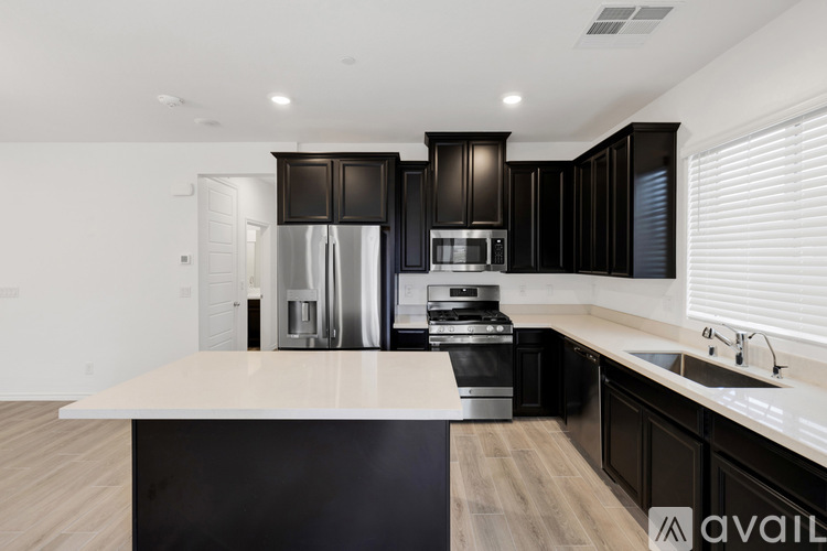 A modern kitchen with black cabinets and stainless steel appliances.