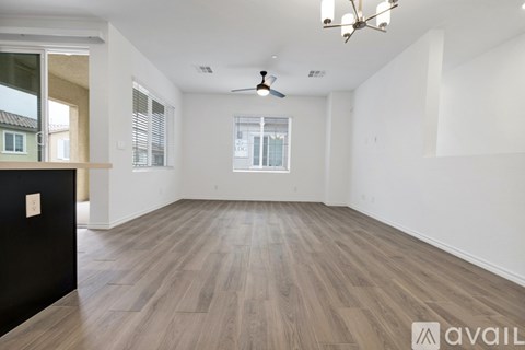 A spacious room with wooden flooring and a ceiling fan.