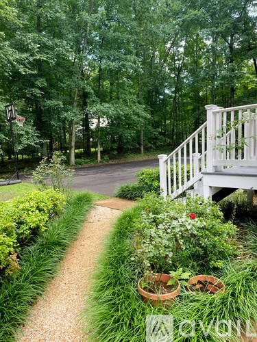 A garden path with a white railing and potted plants.