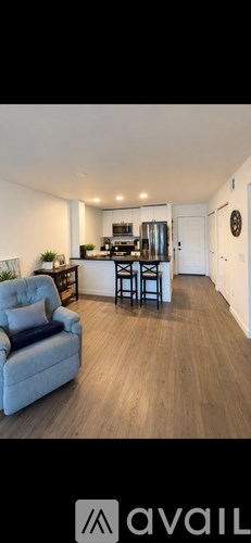 A living room with a grey couch and a kitchen in the background.