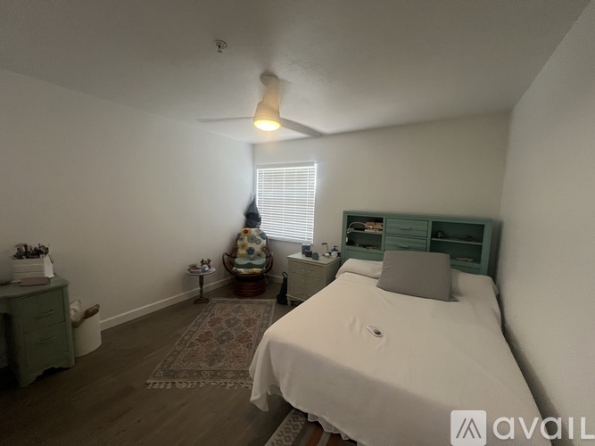 A bedroom with a bed, nightstand, and a fan.