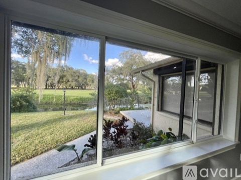 A window with a view of a green lawn and trees.