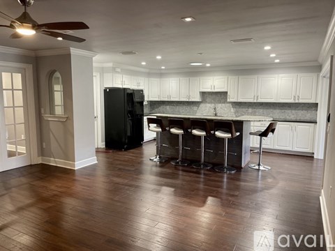 A kitchen with a black refrigerator and white cabinets.
