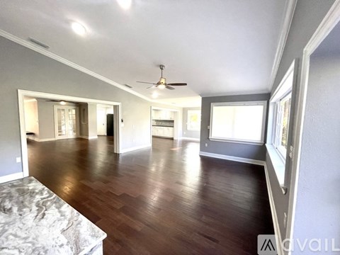 A spacious room with wood flooring and a ceiling fan.