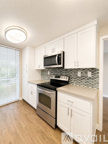 A kitchen with white cabinets and a black microwave above the stove.