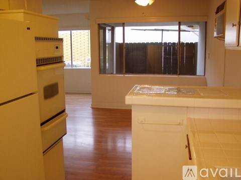 A kitchen with white appliances and wooden floors.