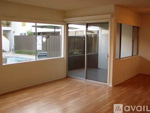 A room with wooden floors and a glass door leading to a balcony.