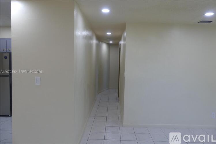A long hallway with a door at the end and a sign that says "available".
