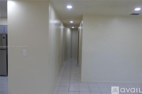A long hallway with a door at the end and a sign that says "available".