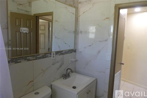 A bathroom with a toilet, sink, and mirror.