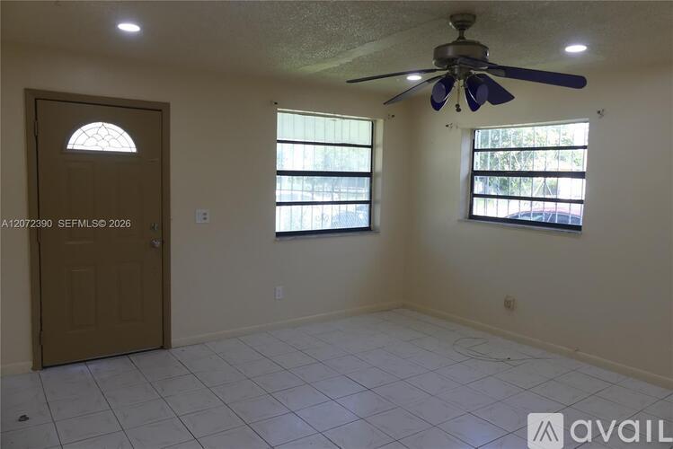 A room with a ceiling fan and two windows.