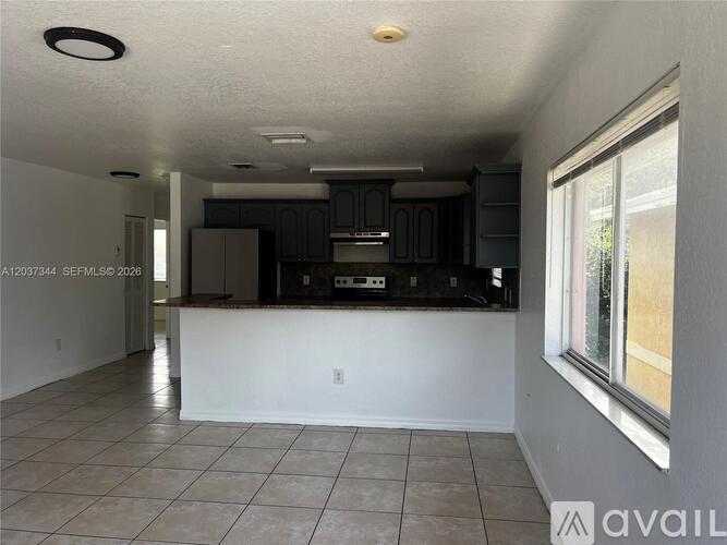 A kitchen with a white countertop and dark cabinets.