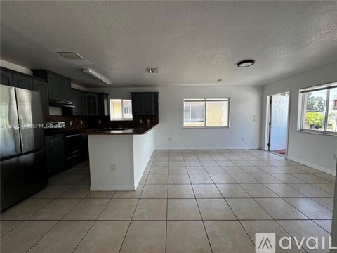A kitchen with black cabinets and a white island.