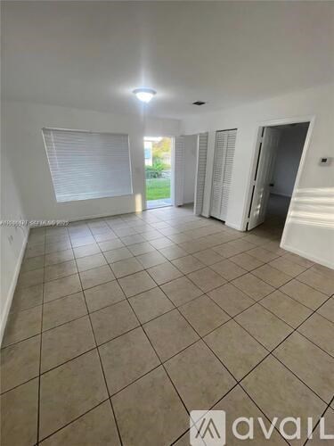 A spacious room with tiled flooring and white walls.