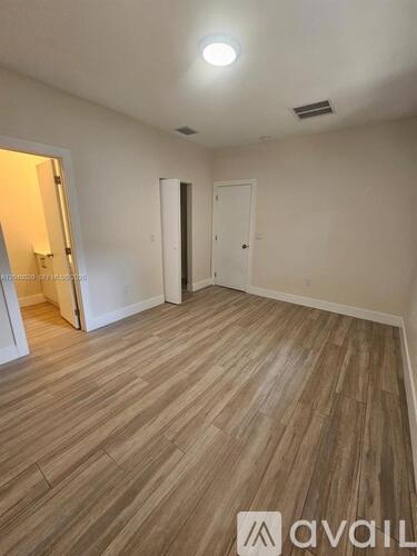 A room with wooden flooring and two doors.